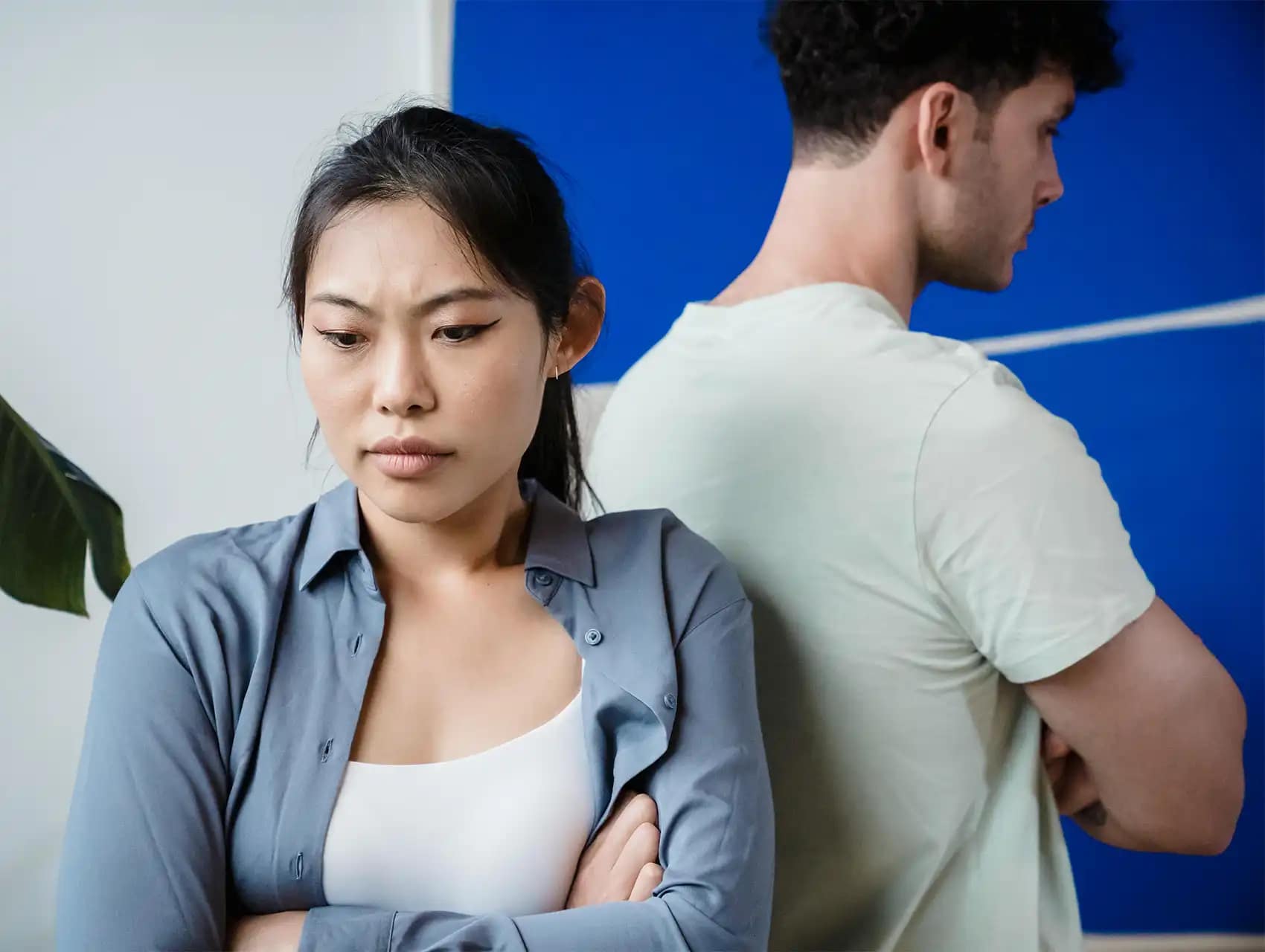 Mujer preocupada y hombre molesto de espaldas tras una discusión – conflictos detrás de las peleas de pareja