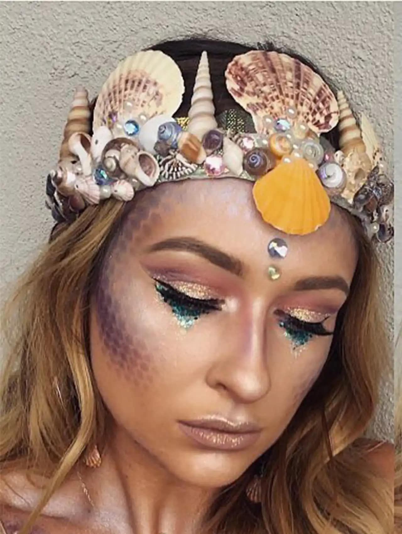 Mermaid-inspired halloween makeup looks with seashell crown, glitter tears, and shimmery scales.