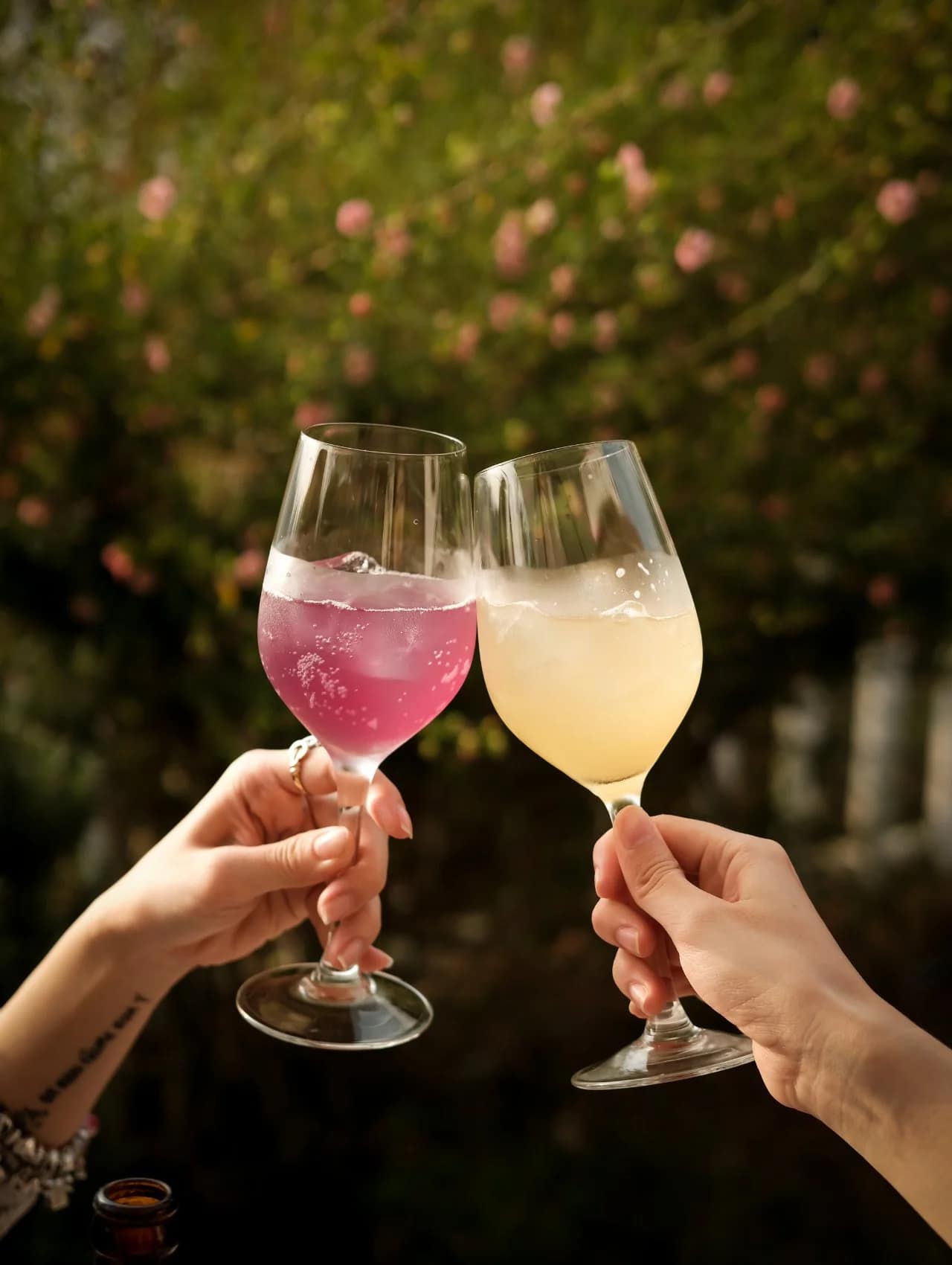 Two hands toasting colorful summer cocktails outdoors, a refreshing drink idea for 4th of july party ideas