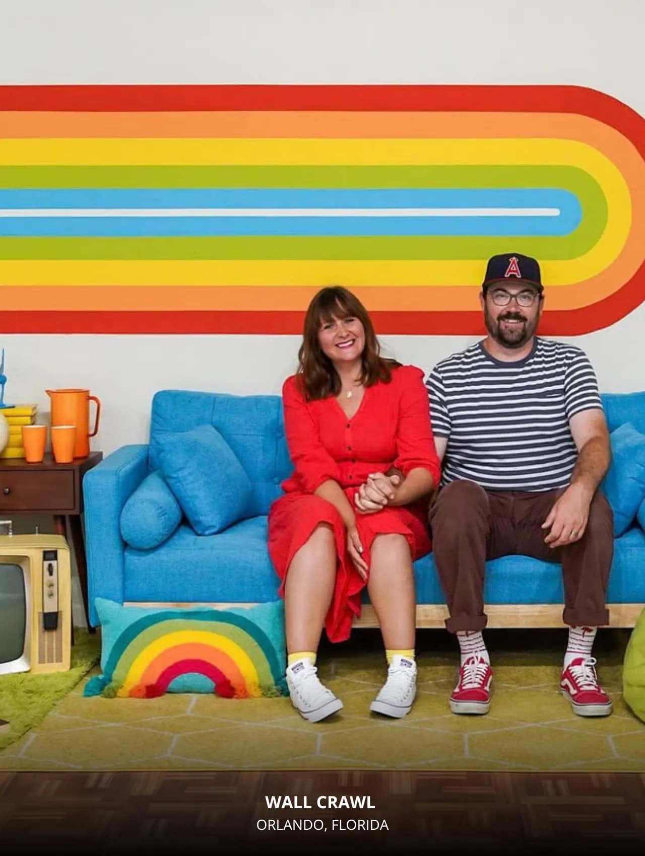 Couple posing on a retro blue couch in the rainbow set at Wall Crawl Orlando – Top Locations in Orlando to Take Beautiful Photos for Your Instagram.