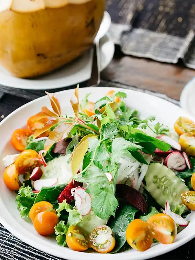 a plate of salad with vegetables and greens