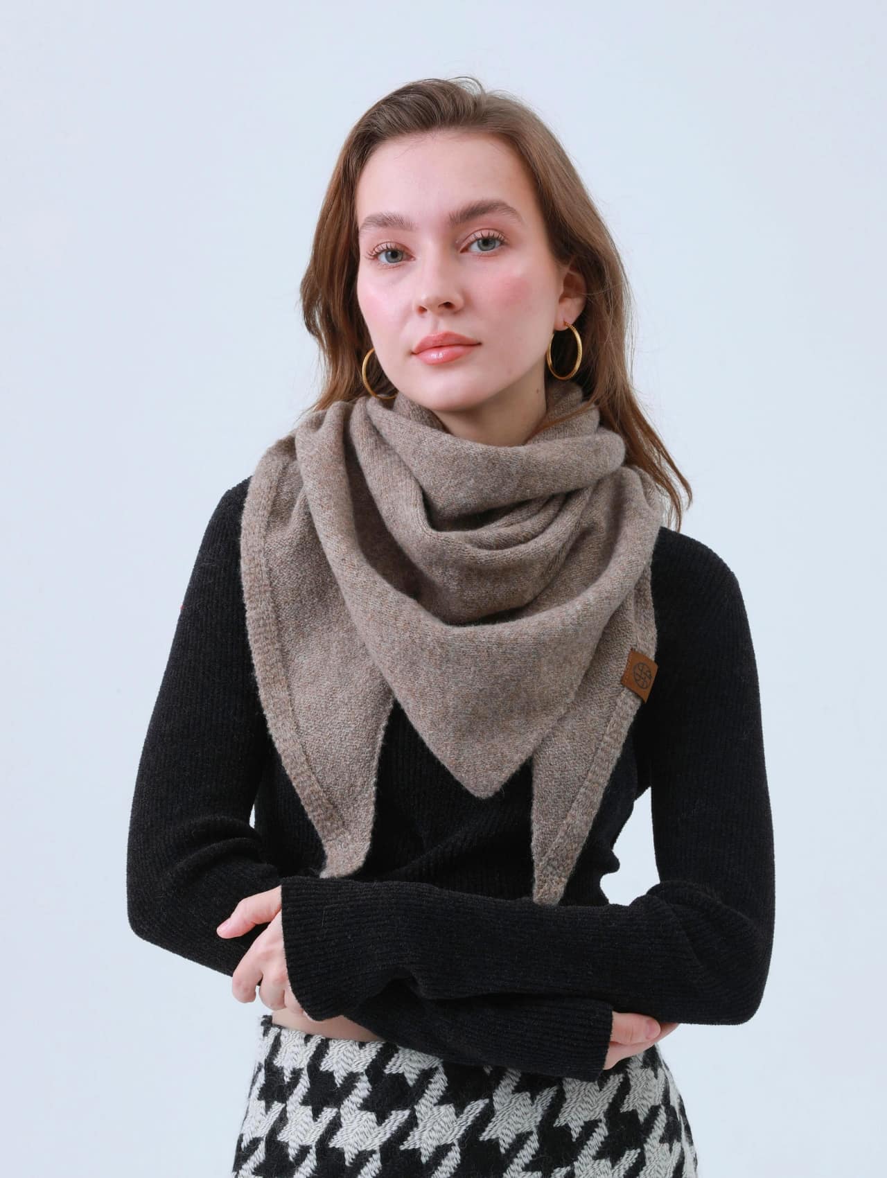 Woman wearing a cozy scarf with a fitted black sweater and houndstooth skirt, representing elegant and sexy winter outfits.