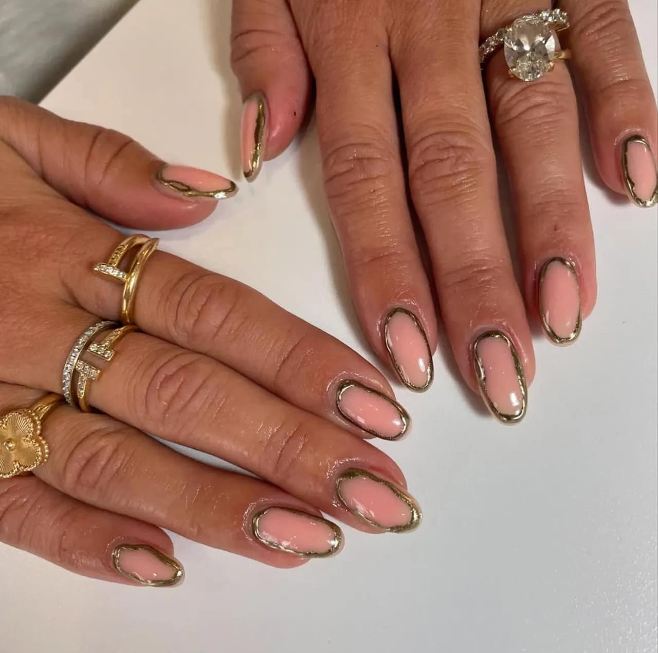 Diseños de uñas acrílicas francesas con borde dorado metálico sobre base nude.