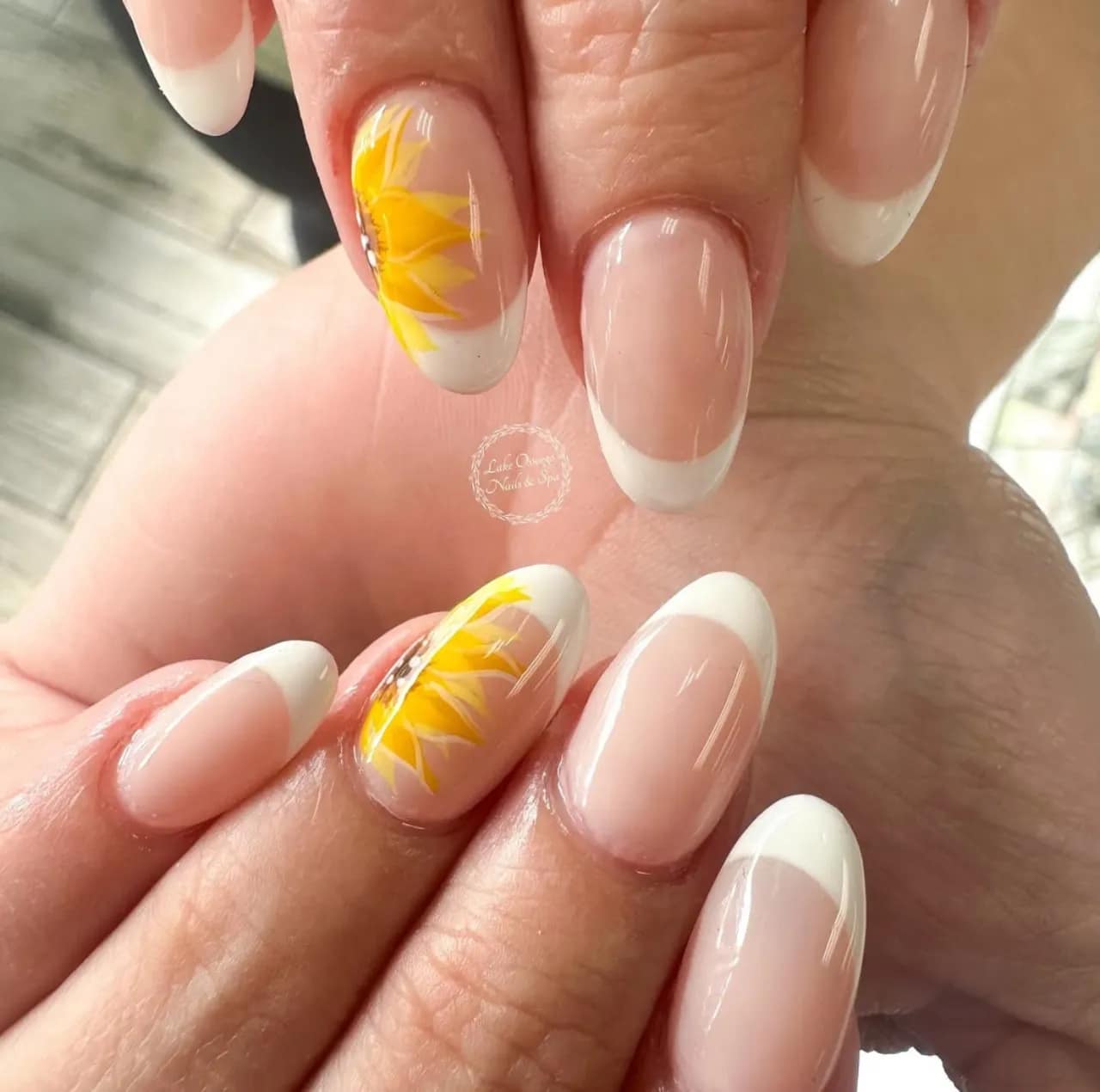 Diseños de uñas acrílicas francesas con girasoles pintados a mano sobre base nude.