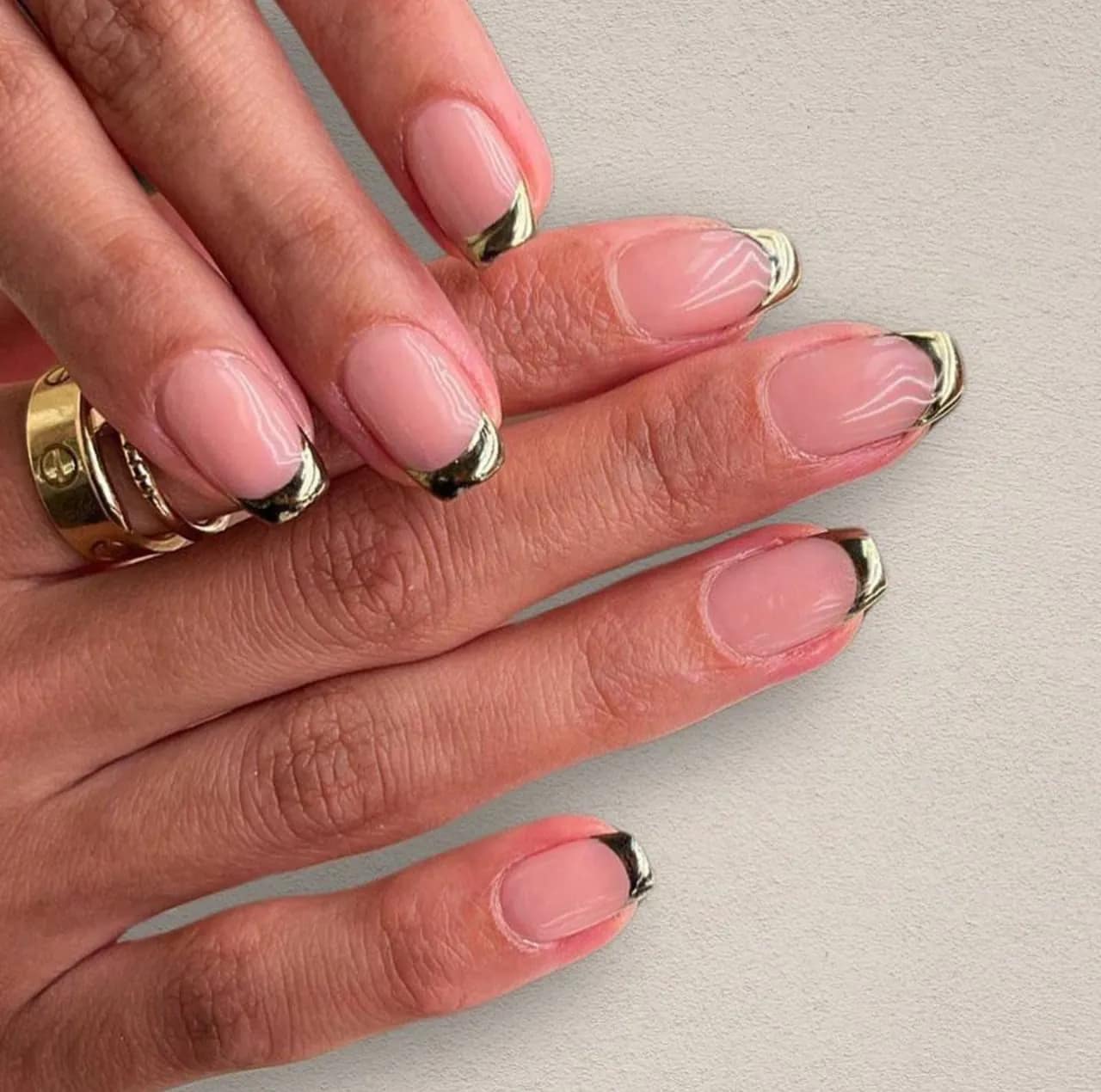 Diseños de uñas acrílicas francesas doradas metalizadas con base nude y acabado elegante.