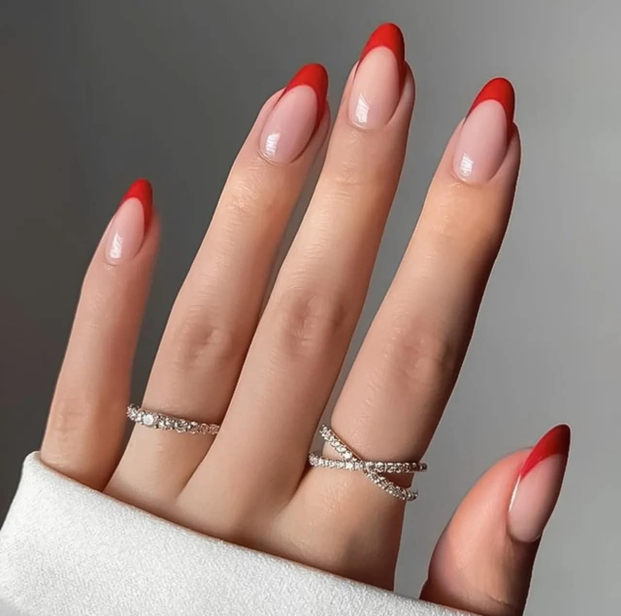 Diseños de uñas acrílicas francesas rojas en forma almendrada con acabado brillante