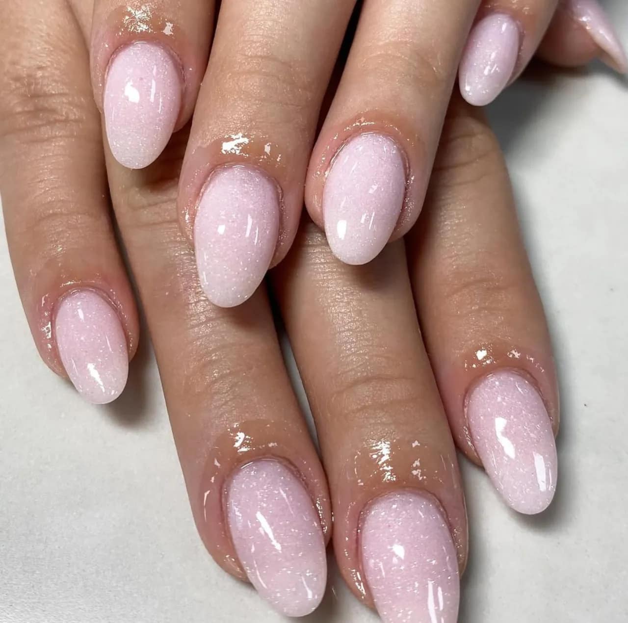 Diseños de uñas acrílicas rosas con glitter sutil y forma almendrada.
