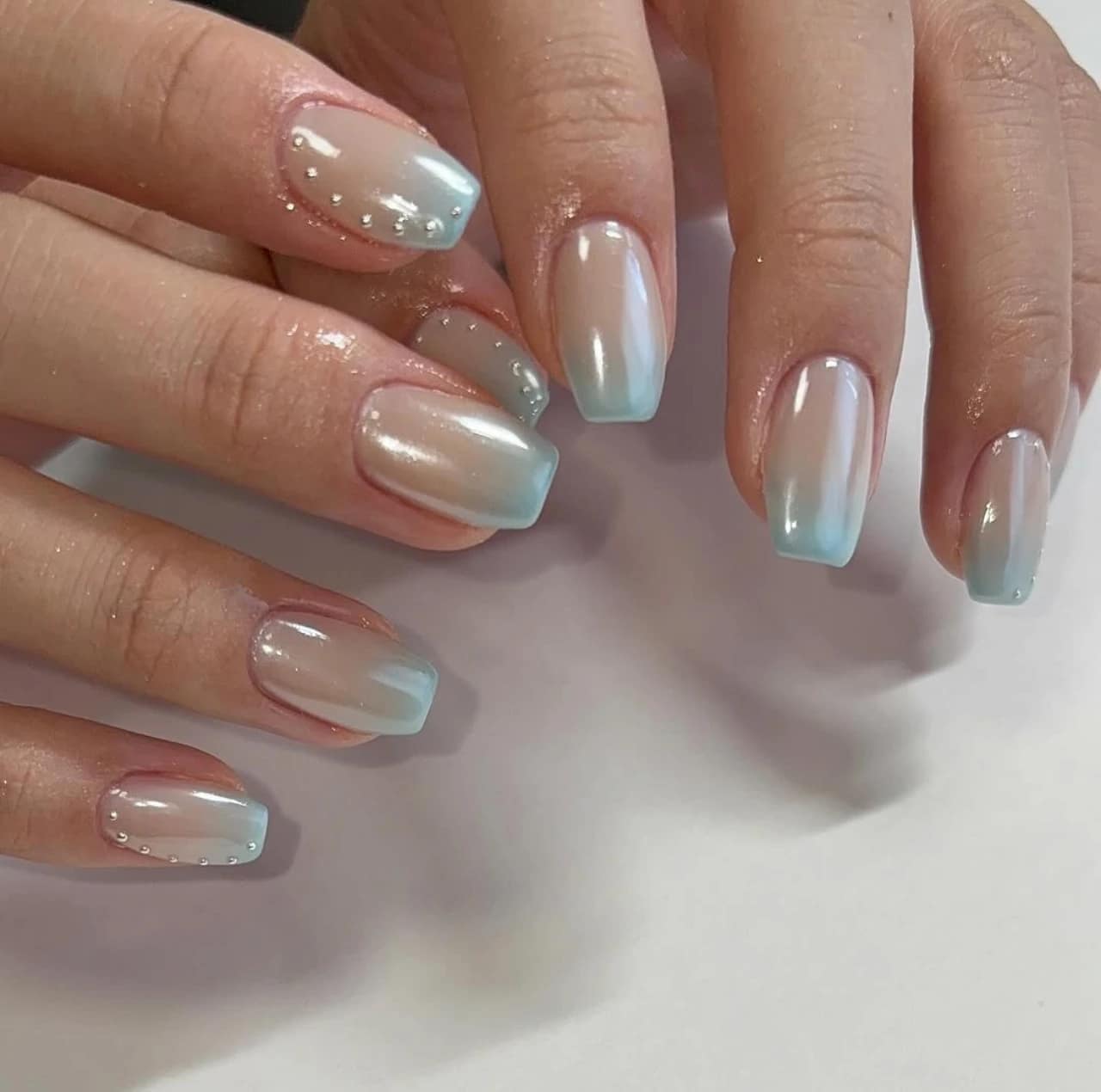 Diseños de uñas acrílicas degradadas azules metalizadas con efecto perlado.