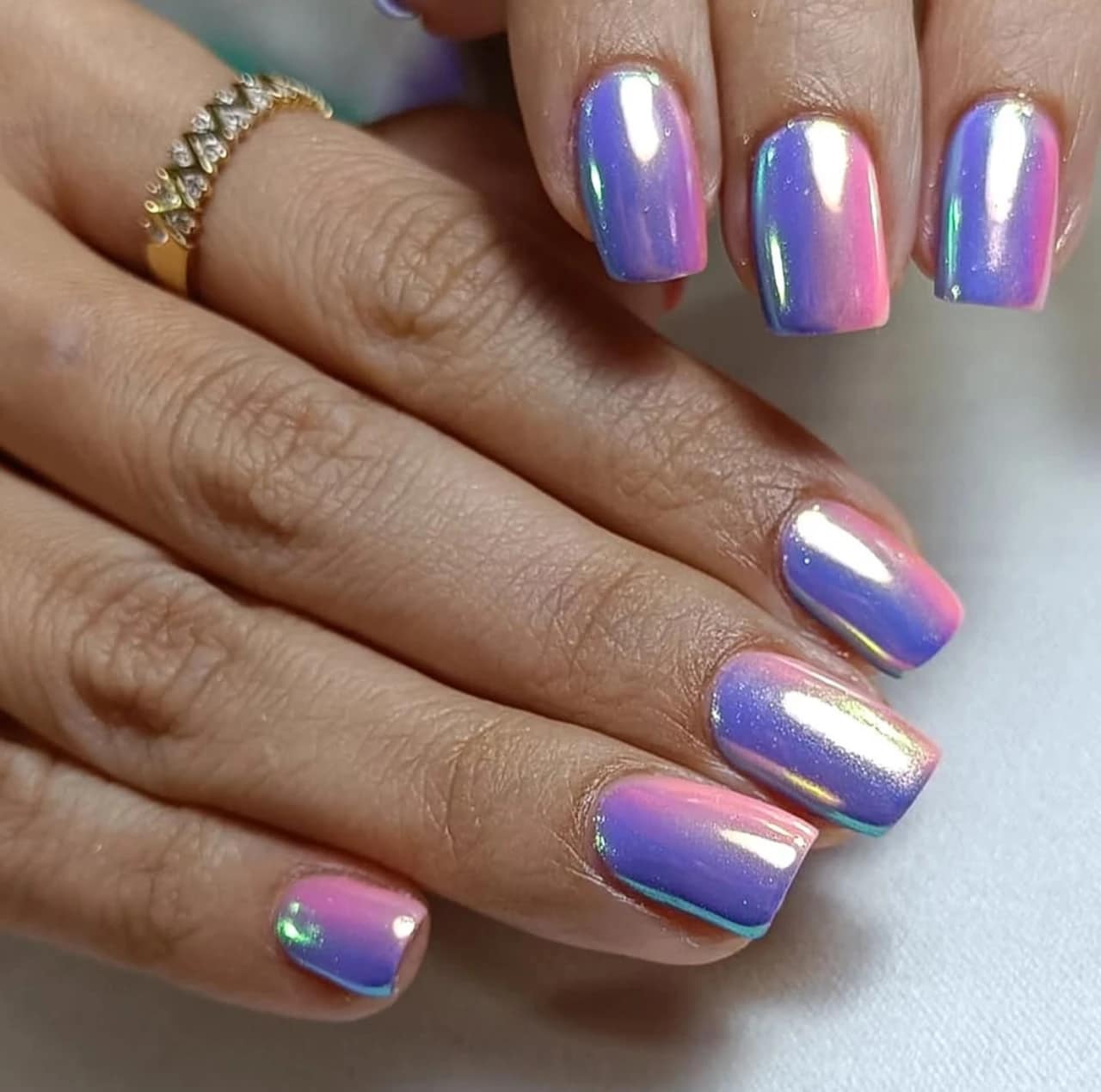 Diseños de uñas acrílicas tornasoladas con acabado espejo en tonos rosa y morado.