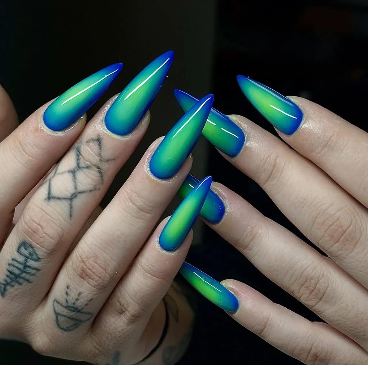 Efecto aura en uñas con degradado verde y azul en uñas largas estilo estileto.