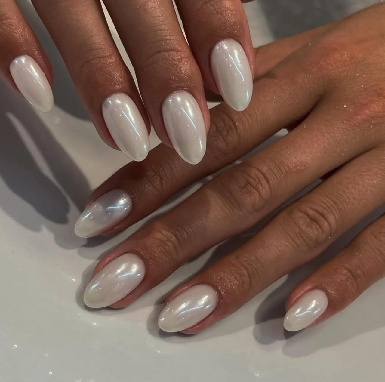 Diseño de uñas perladas brillantes y elegantes con acabado nacarado.