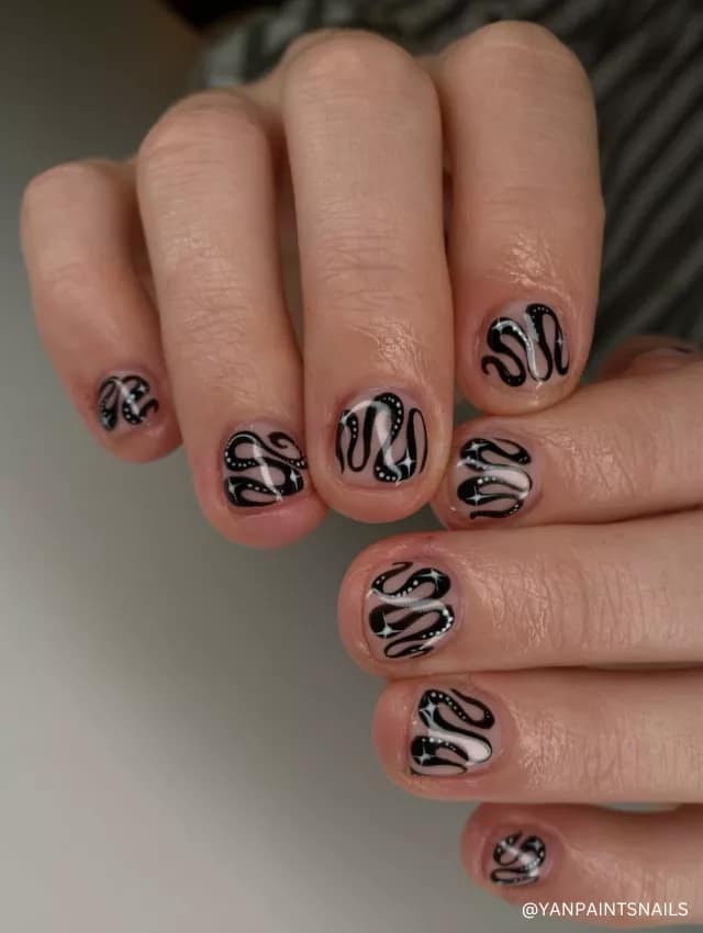 A playful black and white wavy swirl nail design on a nude base with intricate details.