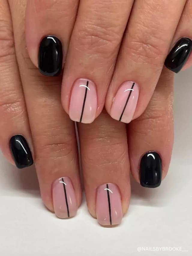 A modern minimalist nail design featuring glossy black nails and nude nails with sleek black line accents.