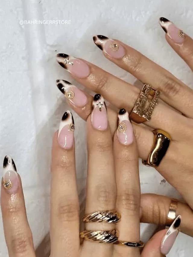 Almond-shaped nails with smokey black tips and gold charm decals.