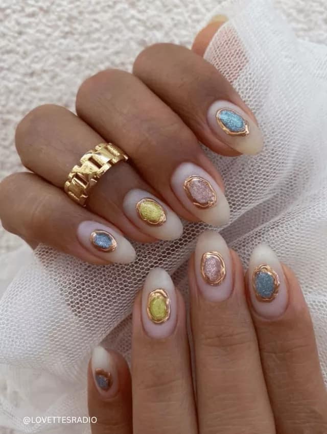 Soft ombré nude nails with colorful 3D gemstone frames.
