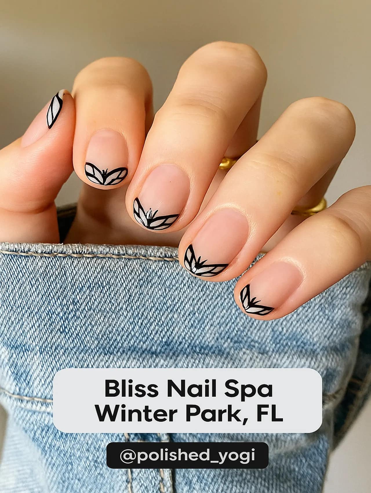 Close-up of a hand with nude nails and black leaf line art tips from Bliss Nail Spa in Winter Park, FL.