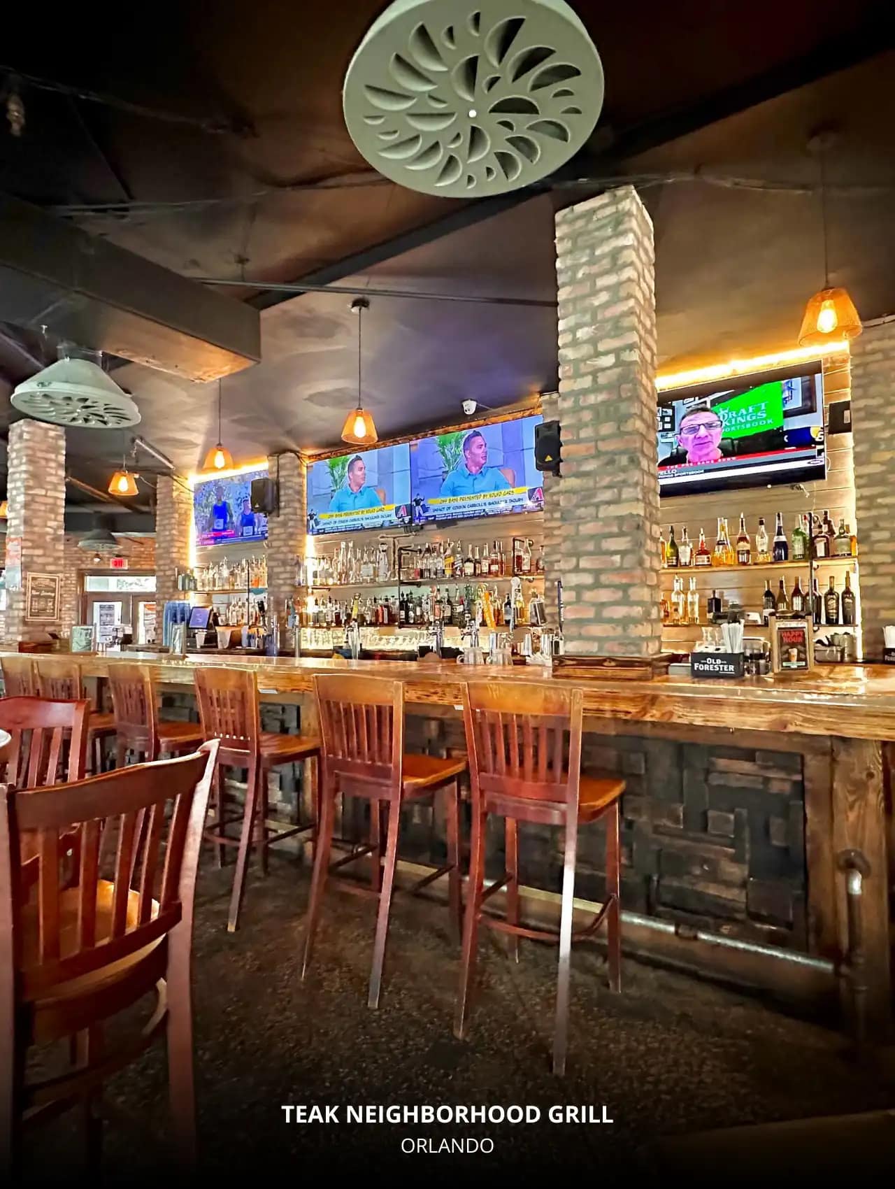 Brick-lined bar at Teak Neighborhood Grill with multiple sports screens, Orlando Sports Bars