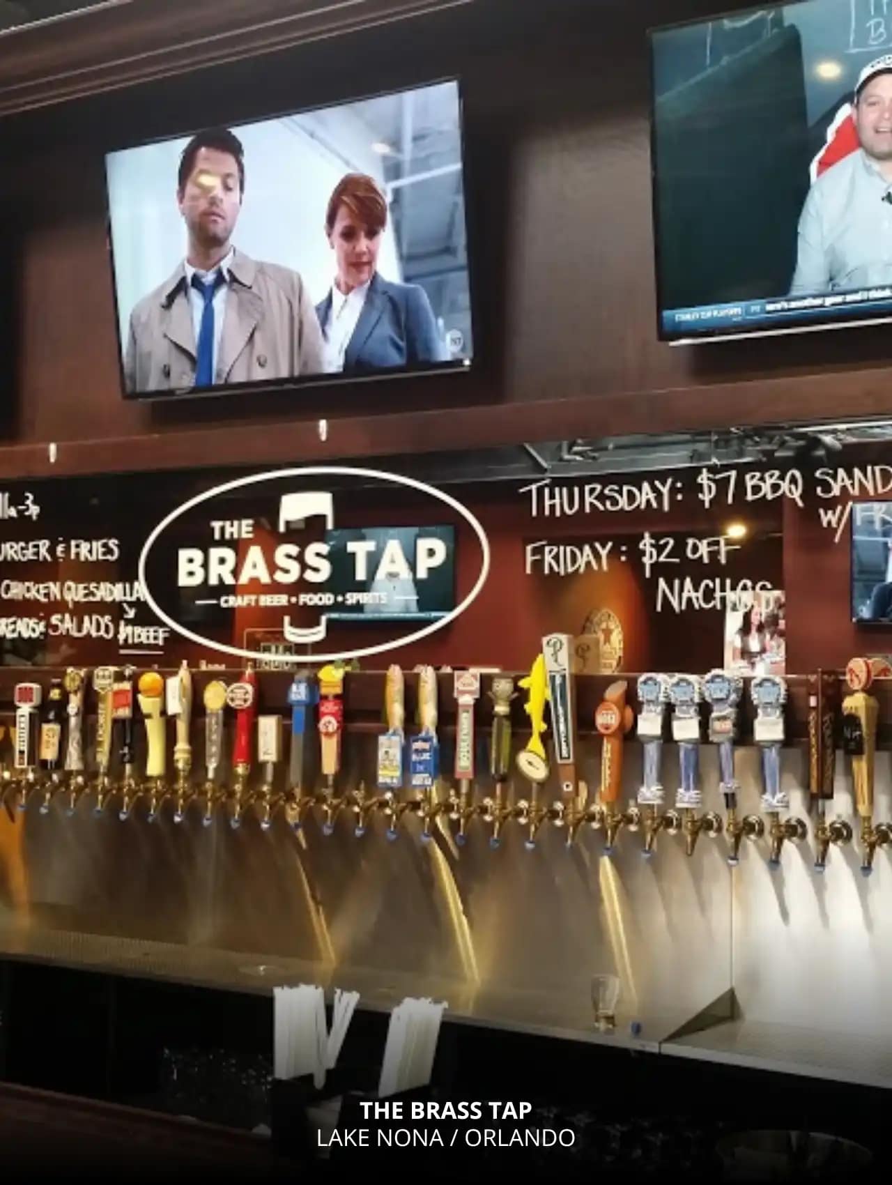 Interior view of The Brass Tap Lake Nona showcasing TVs and a large craft beer tap selection, one of the best sports bars in Orlando.